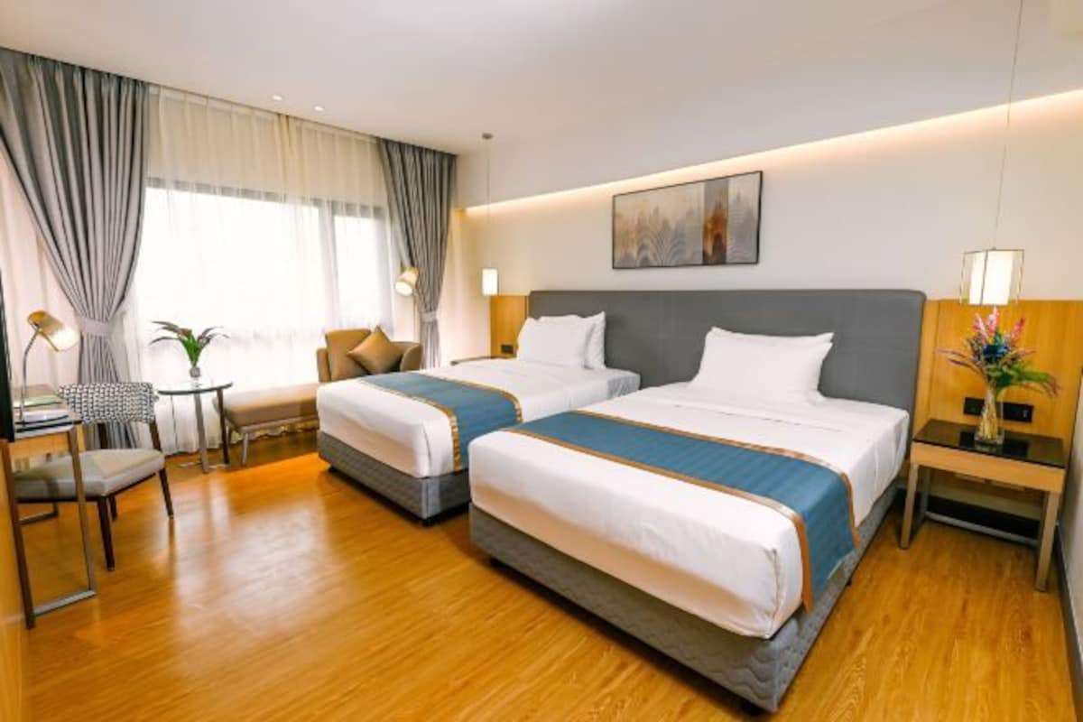 Habitación de hotel con dos camas, un escritorio y una silla.