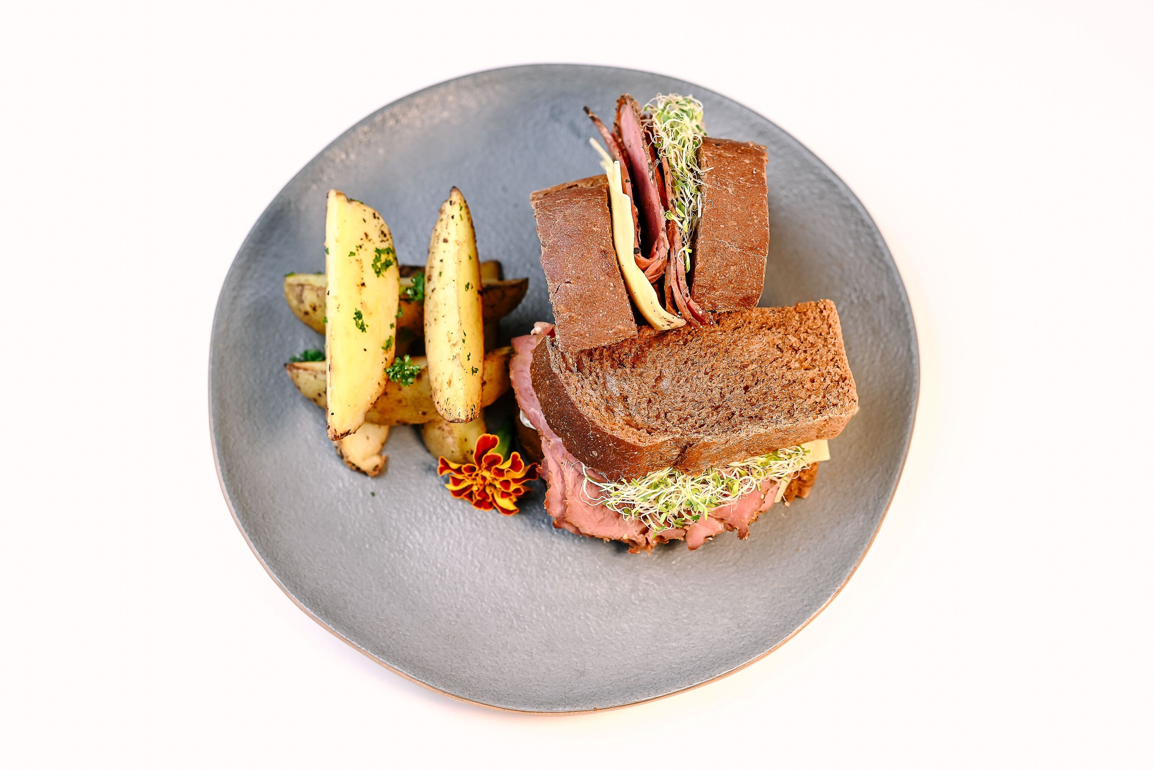 A plate with a sandwich and roasted potatoes.