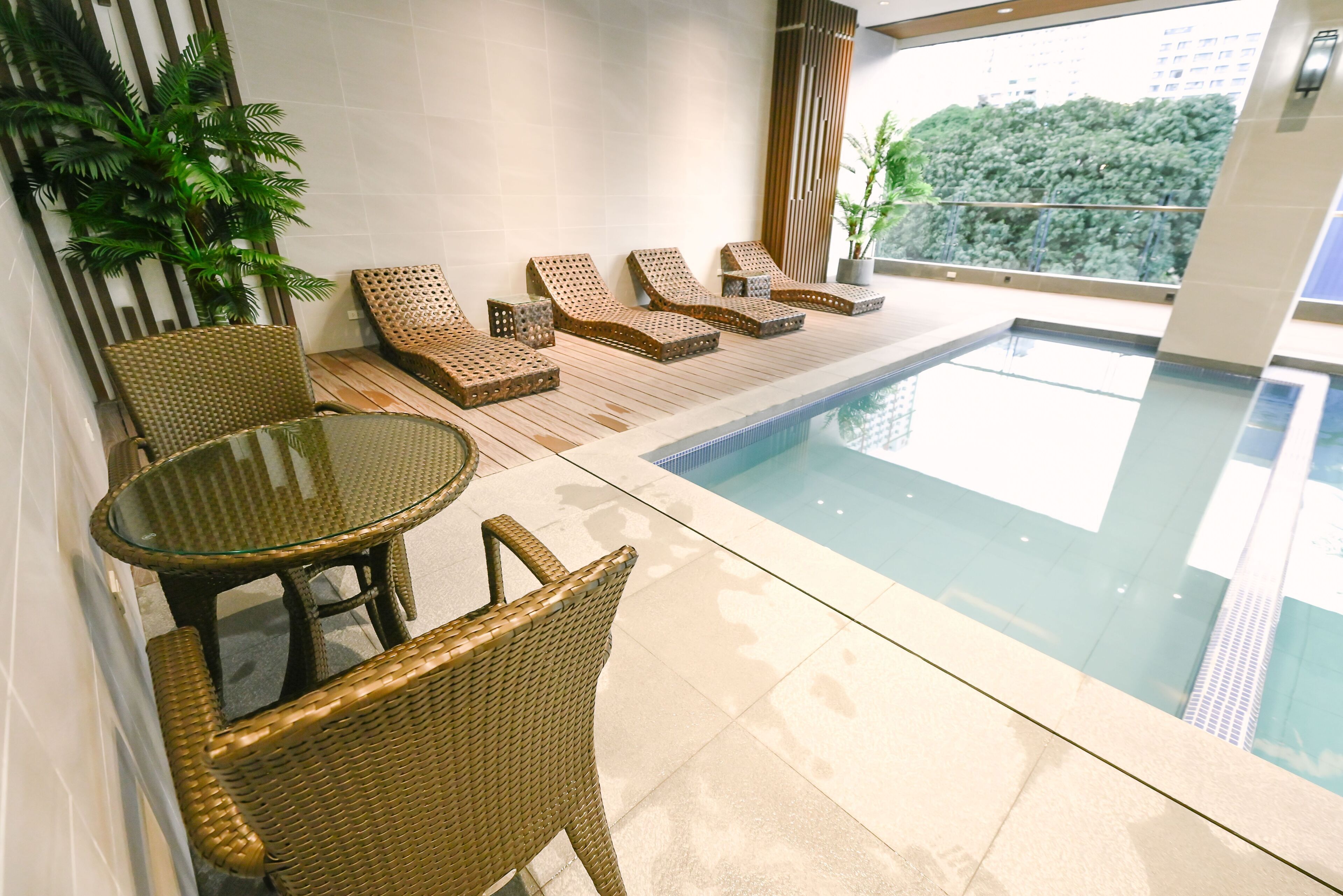 A pool area with wicker furniture and a glass table.