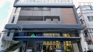 Um hotel moderno com entrada imponente, vários andares e placa visível do 'Arden Hotels Suites'.