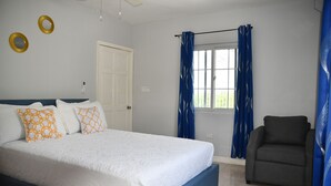 Un dormitorio con una cama, una silla, una ventana con cortinas y una puerta.