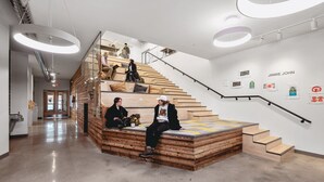 A modern interior with a wooden staircase, a seating area, and artwork on the walls. - Pine Tree House 316 (Traverse City)