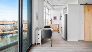 A modern kitchen with a view of a river, a dining area with a table and chairs, and a large window. - Pine Tree House 316 (Traverse City)