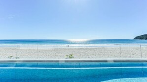 A clear blue sky, a sandy beach, and a swimming pool.