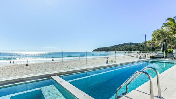 A pool with a clear view of the beach and ocean.