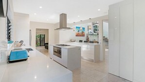 A modern kitchen with a central island, built-in oven, and a large window. - The Lighthouse on Noosa Hill (Noosa Heads)