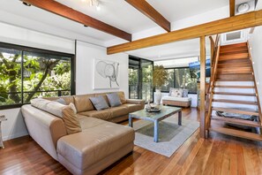 Relax in this stylish living room with a comfortable L-shaped sofa, wooden coffee table, and a staircase leading to an upper level.