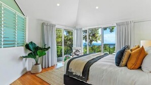 A bedroom with a large bed, a potted plant, and a view of the outdoors.
