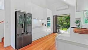 A modern kitchen with white cabinetry, a stainless steel refrigerator, and a wooden floor.