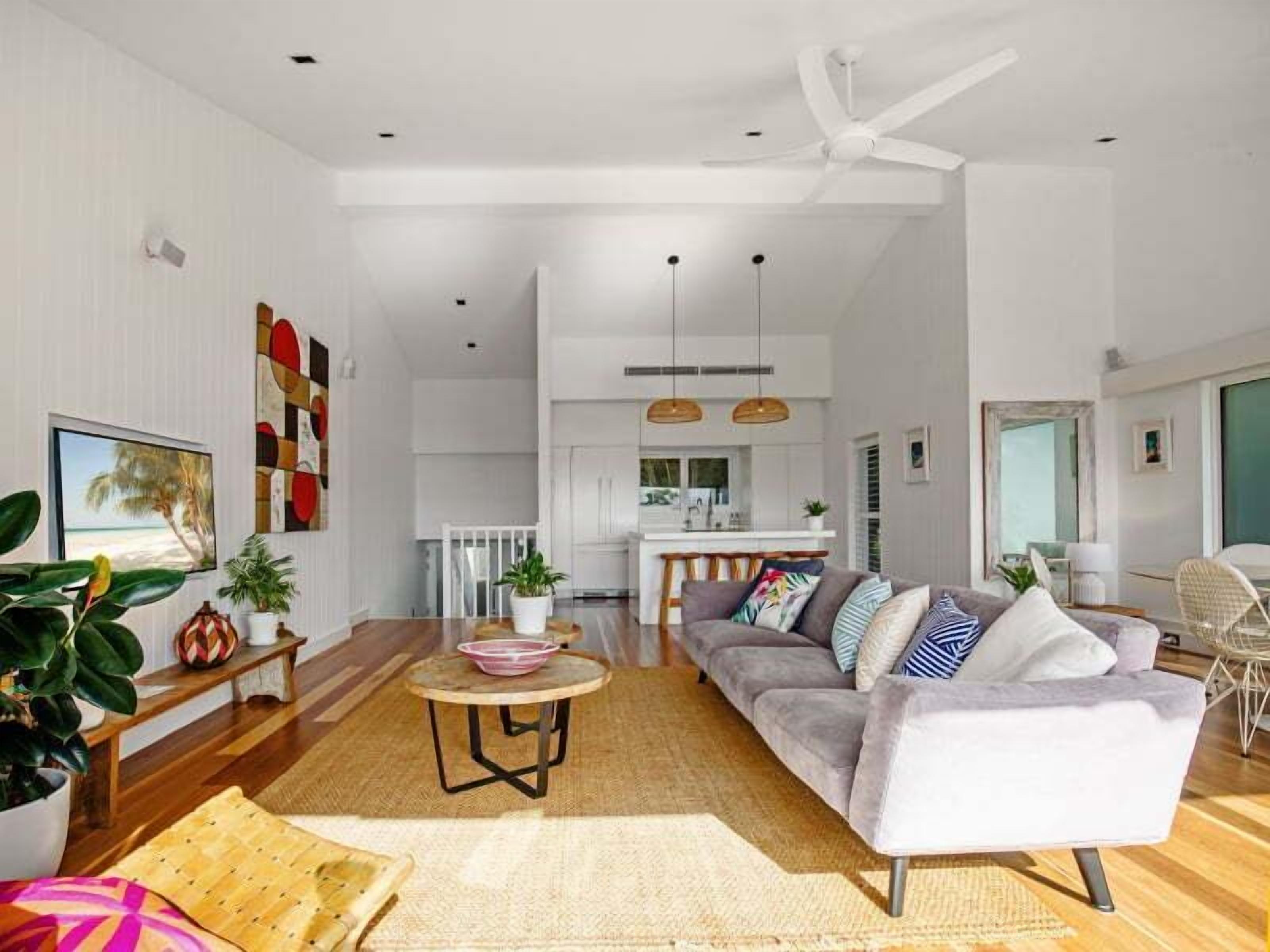 A spacious living room with a sofa, coffee table, and potted plants.