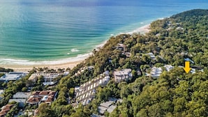 Eine Luftaufnahme einer Küstenregion mit Strand, dichter Vegetation und Wohngebäuden.