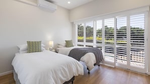 Un dormitorio con dos camas, ventilador de techo y vistas amplias a través de ventanas grandes.