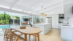 Una cocina amplia con una isla grande, electrodomésticos modernos y un comedor con vistas a la piscina.
