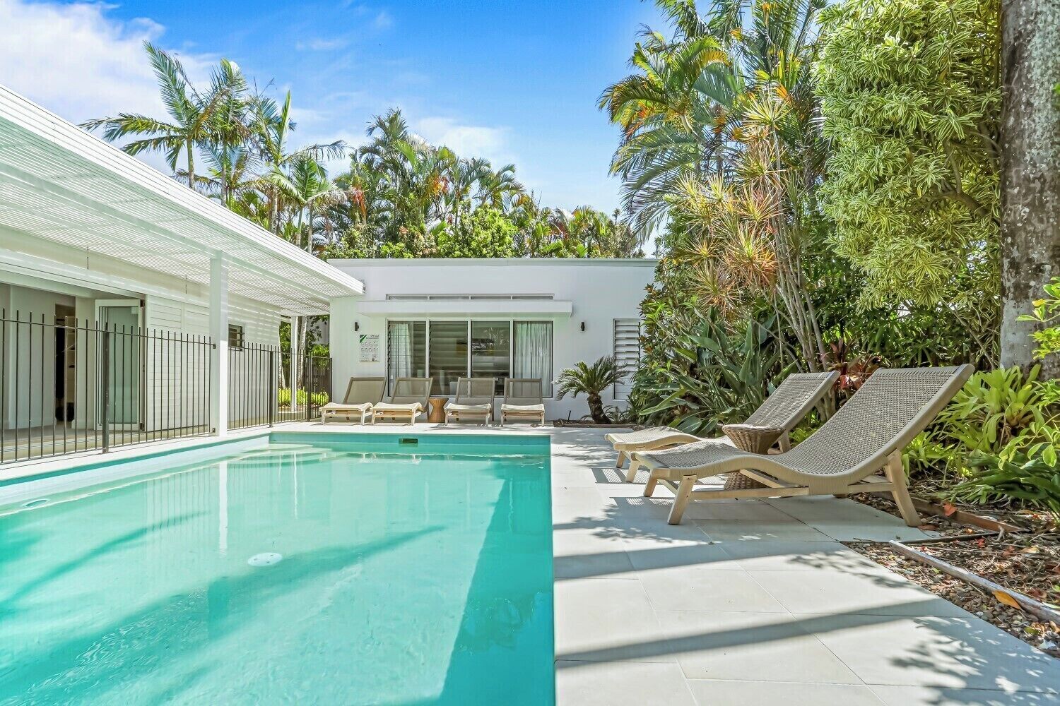 A modern pool area with lounge chairs and a clear blue pool.