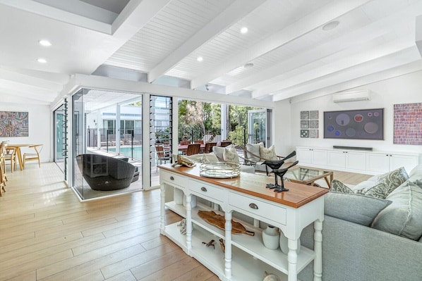 Enjoy seamless indoor-outdoor living in this spacious area with a dining table, comfortable seating, and a flat-screen TV.