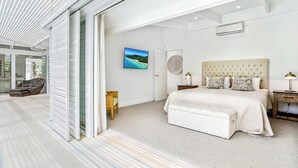 Un dormitorio moderno con una cama grande, vistas al exterior y un área de descanso con una silla y una mesa.