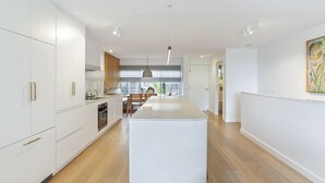 A modern kitchen with white cabinetry, a central island, and a dining area with wooden chairs.