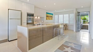A modern kitchen with a central island, stainless steel appliances, and a view of the outdoors. - Comfortable & stylish with rooftop spa (Sunshine Beach)