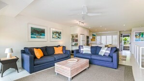 A modern living room with two sofas, a coffee table, and a ceiling fan. - Comfortable & stylish with rooftop spa (Sunshine Beach)