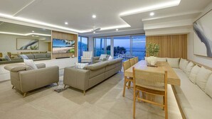 Ein modernes Wohnzimmer mit einer großen Couch, einem Esstisch und Blick ins Freie.