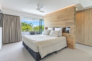 Relax in this serene bedroom with a large bed, TV, and a view of lush greenery outside.