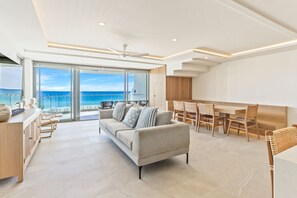 Relax in this spacious living area with a comfortable sofa, dining table, and kitchenette, offering a balcony with a sea view.