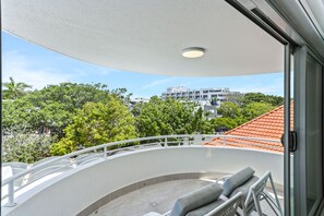 Enjoy the view from this balcony with a seating area and lush greenery in the background.