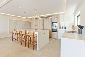 Enjoy cooking and socializing in this kitchen with a central island, sleek cabinetry, oven, and stainless steel range hood.