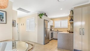 A modern kitchen with a central island, stainless steel appliances, and a dining area with a glass table.