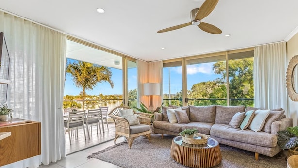 A spacious living room with a large sofa, a coffee table, and a dining area with chairs and a table.