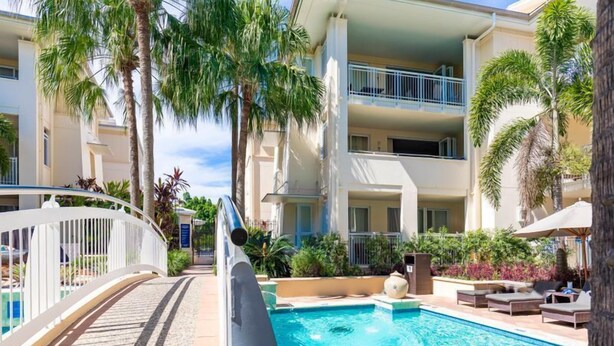A pool area with a clear view of the pool, lounge chairs, and palm trees. - Modern & quiet on Hastings Street (Noosa Heads)
