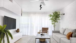 A modern living room with a flat-screen TV, a coffee table, a sofa, and a chair.