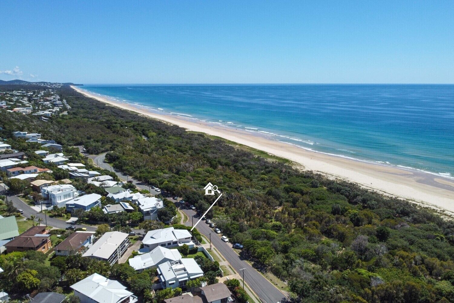 Eine Luftaufnahme einer Küstenregion mit Strand und einer Reihe von Häusern.