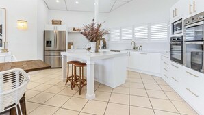 A modern kitchen with white cabinetry, stainless steel appliances, and a central island with stools.