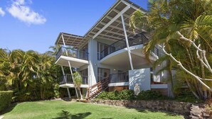 A two-story house with a balcony, a staircase, and a well-maintained lawn.