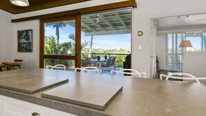 A modern kitchen with a large island, white chairs, and a view of the outdoors.