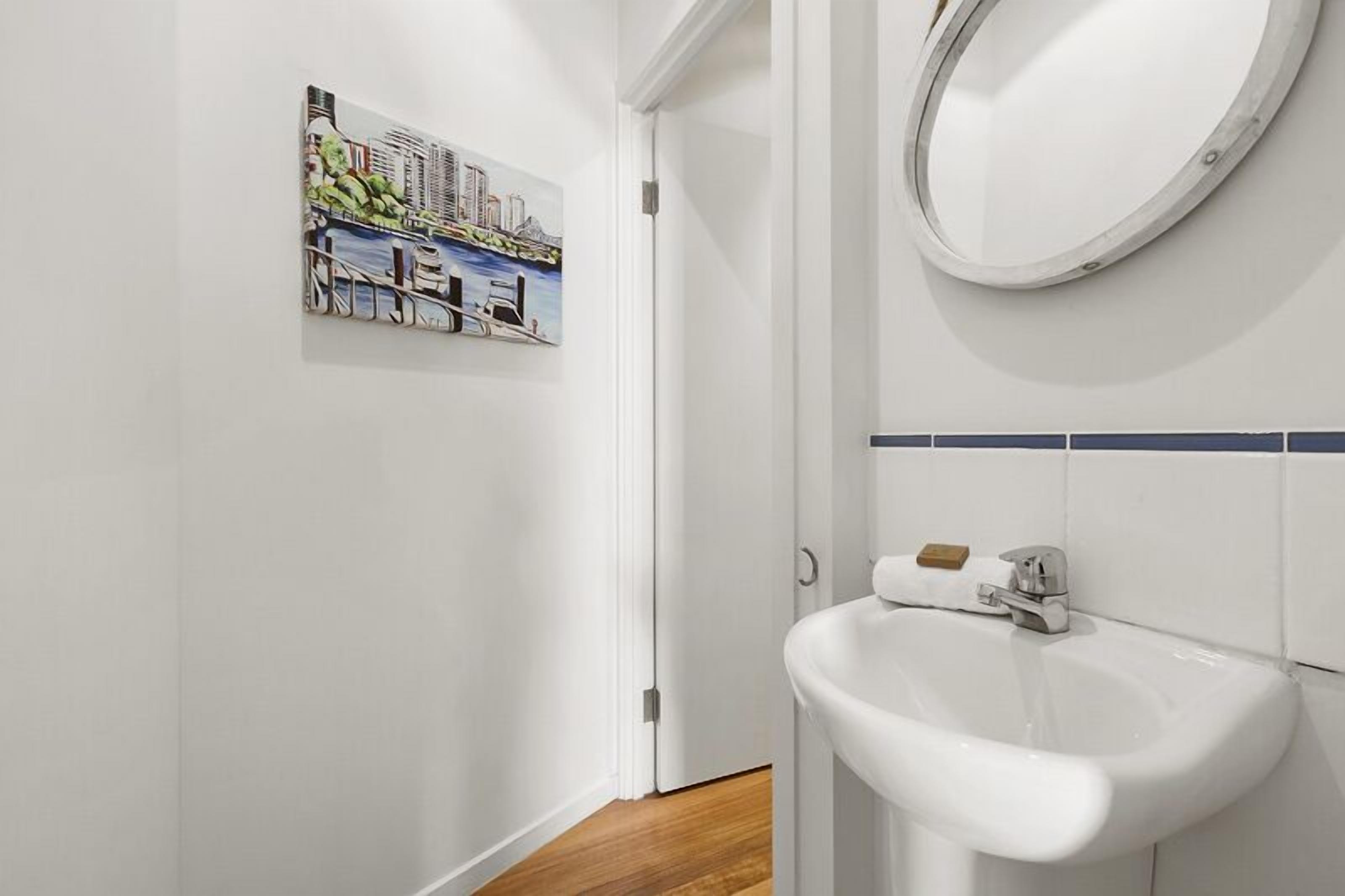 Ein Badezimmer mit einem weißen Waschbecken, einem Spiegel und einem Stadtbild an der Wand.