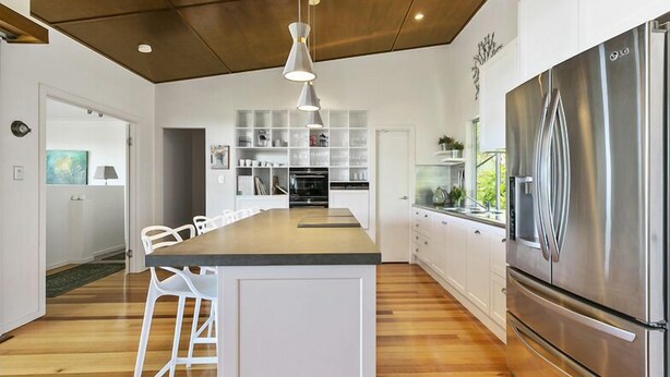 A modern kitchen with a central island, stainless steel appliances, and white cabinetry.