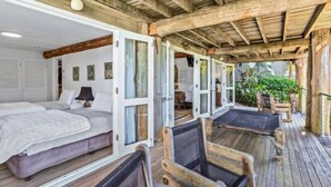 Une terrasse en bois avec un lit et deux chaises longues.