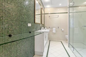 Bathroom features a large mirror, glass shower enclosure, and a white toilet.