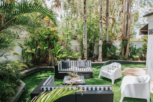 Relax in a serene outdoor space surrounded by lush greenery and comfortable seating options.