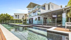Et moderne hus med to etager, en swimmingpool og en overdækket terrasse.