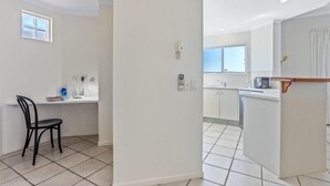 A modern kitchen with white cabinets, a countertop, and a window.
