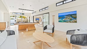 A modern hotel lobby with a reception desk, seating area, and a large window offering a view of the sea.