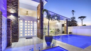 A modern house with a swimming pool, stone pillars, and a glass door entrance. - Exquisite Riverside Living, Noosaville (Noosaville)