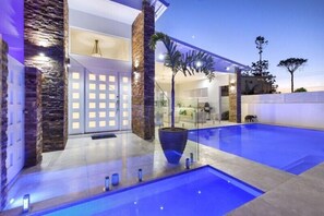 A modern house with a swimming pool, stone pillars, and a glass door entrance. - Exquisite Riverside Living, Noosaville (Noosaville)
