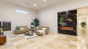 Un salon spacieux avec un ensemble de canapés beige, une table basse et une cheminée.