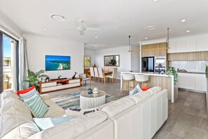 Enjoy a spacious living area with a sofa set and dining table, a sleek kitchen with central island, and a large balcony with ocean views.