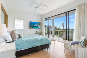 Relax in this serene bedroom with a large bed, flat-screen TV, and balcony offering a view of the surrounding landscape.