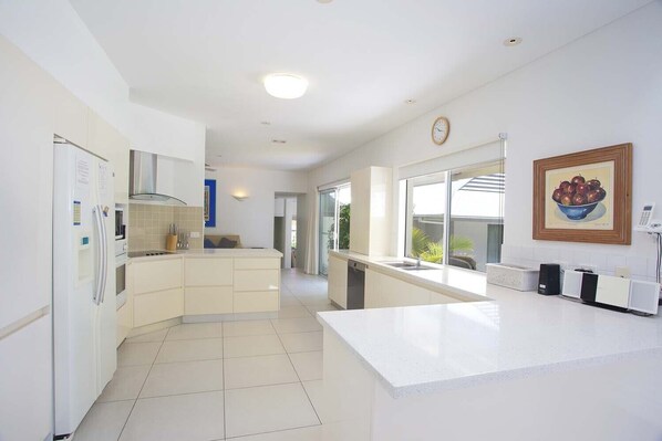 Una cocina moderna con armarios blancos, una isla central y un amplio ventanal que proporciona luz natural.